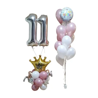 קישוט בלונים עם מספרים ליום הולדת, מעמד עם כתר עם הקדשה אישית ושתי ספרות מרחפות מעליו לצד זר בלוני הליום מהמם עם בלון HAPPY BIRTHDAY בראשו.