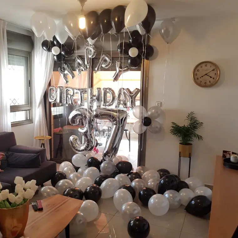 חדר בלונים ליום הולדת בעיצוב קלאסי של שחור כסף לבן, עם אותיות HAPPY BIRTHDAY, שתי ספרות כסופות ושלל בלונים בתקרה ועל הרצפה.